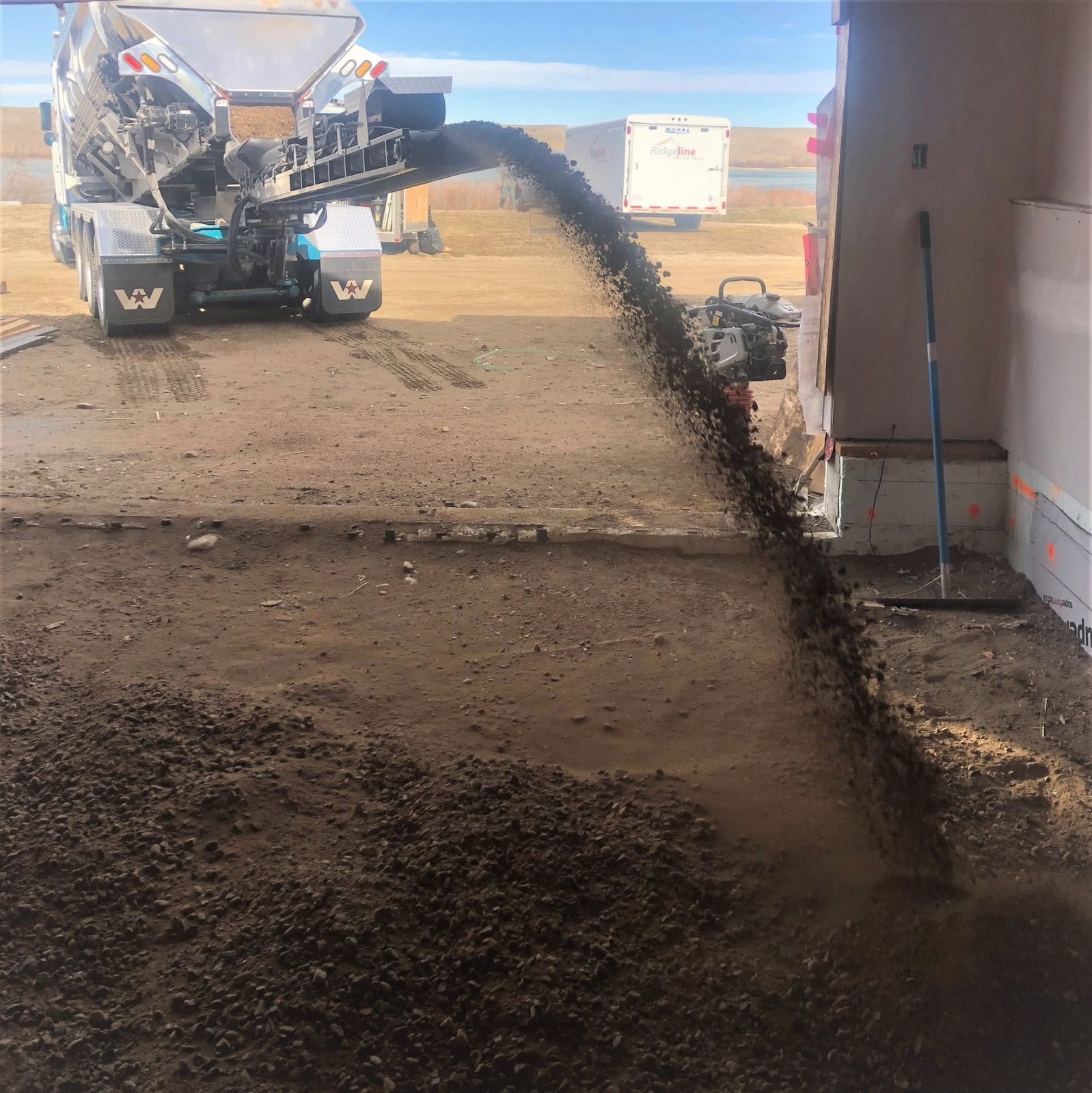 Slinger boom reaching over a house to place gravel in the backyard